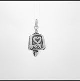 In this video you can see our handcrafted sterling silver, Harmony Charm Bell. It is decorated with the words Hope, Love, Joy, Faith, Peace, as well as hearts, crosses, and a peace symbol with an an open heart for the clapper. 