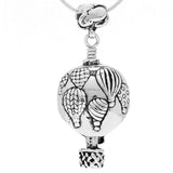 Handcrafted in Sterling Silver, the Hot Air Balloon Bell Pendant is crafted with one side depicting a large Hot Air Balloon, a cloud floats overhead as the bail while the clapper is a hot air balloon's basket. The reverse depicts a sky filled with hot air balloons showing some of their many varied patterns.