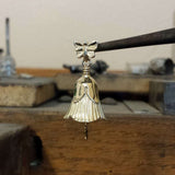 Handcrafted in 10 or 14K, the gold petals of the flower form the body of the bell, the bail is a butterfly fluttering above and a hummingbird hangs from the clapper.